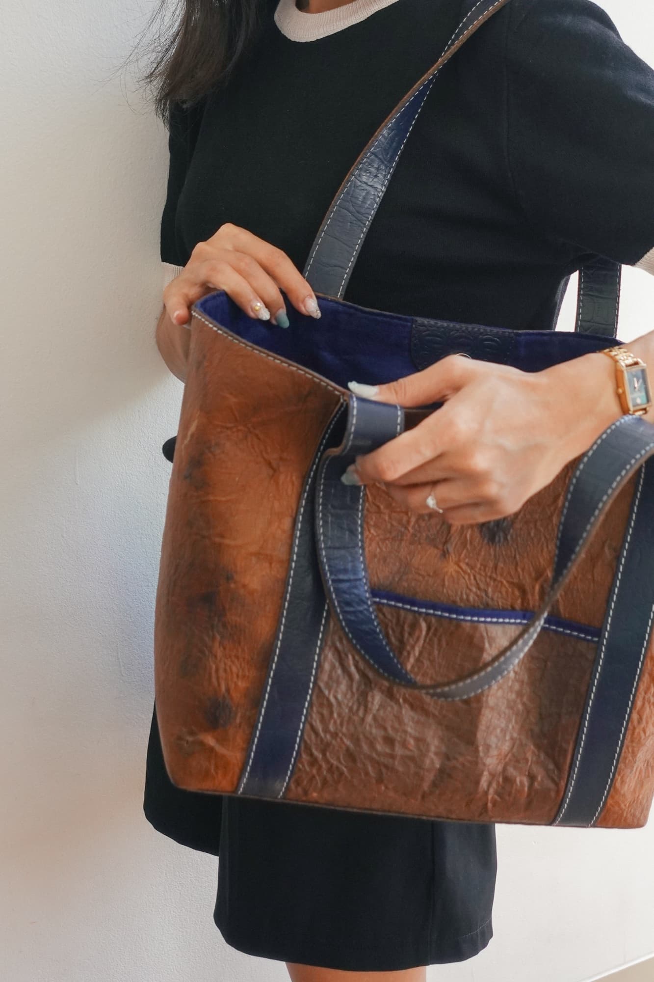 A model carrying a blue-strapped Symbia tote