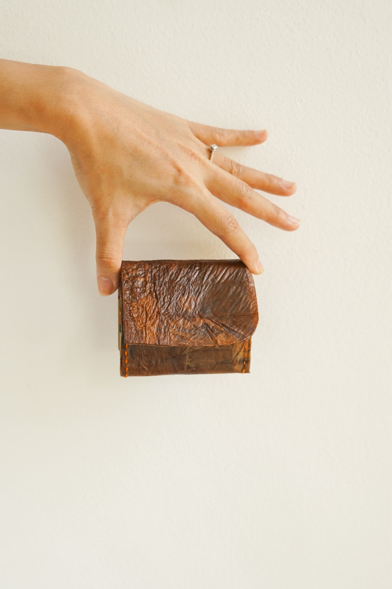 A hand placing a Symbia bioleather wallet