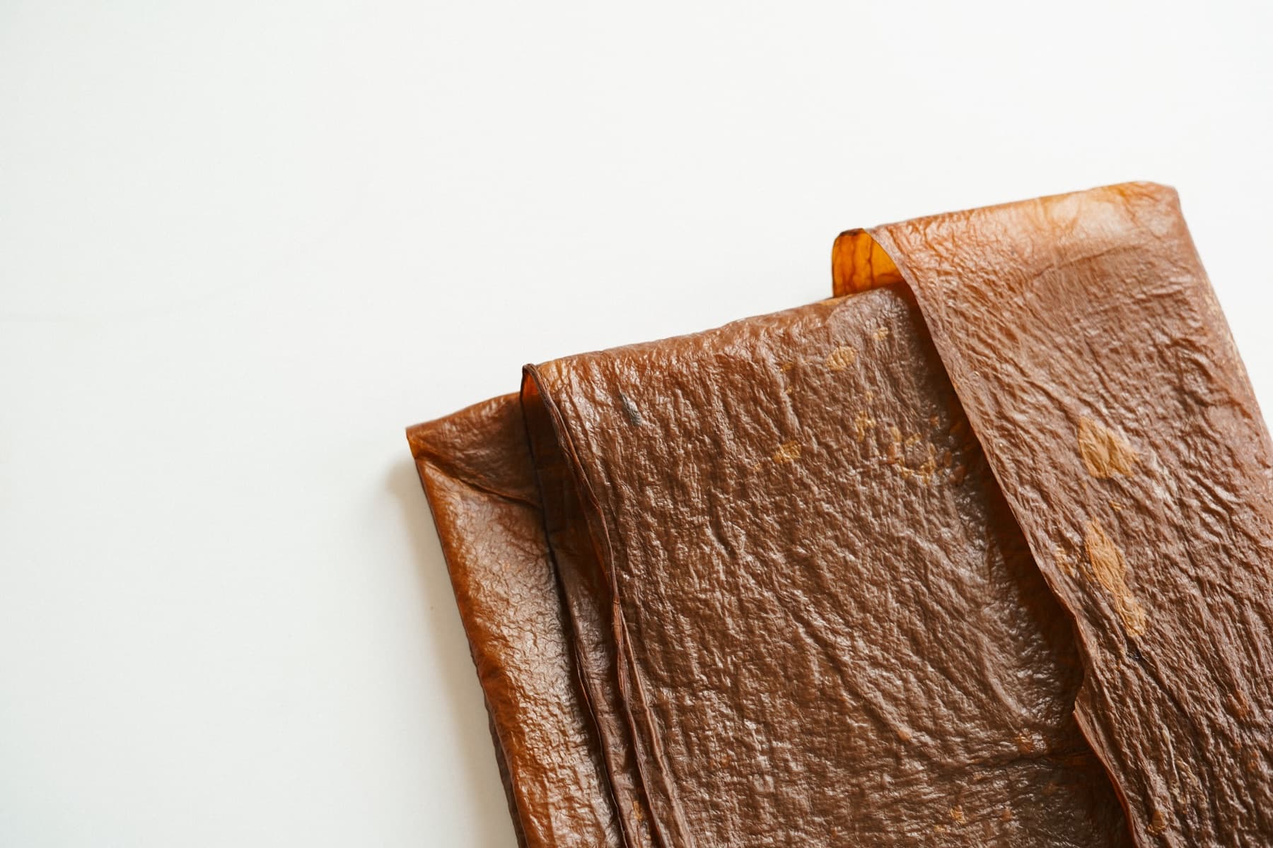 Several finished sheets of Kombucha Bioleather folded and stacked